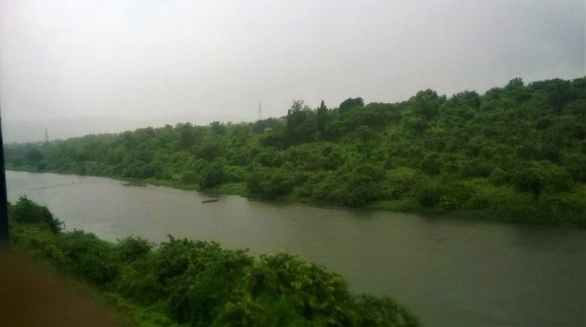 A scenic travel story captured through a train window, revealing rolling green hills, dense forest, and small village homes tucked into the landscape beneath a cloudy sky.
