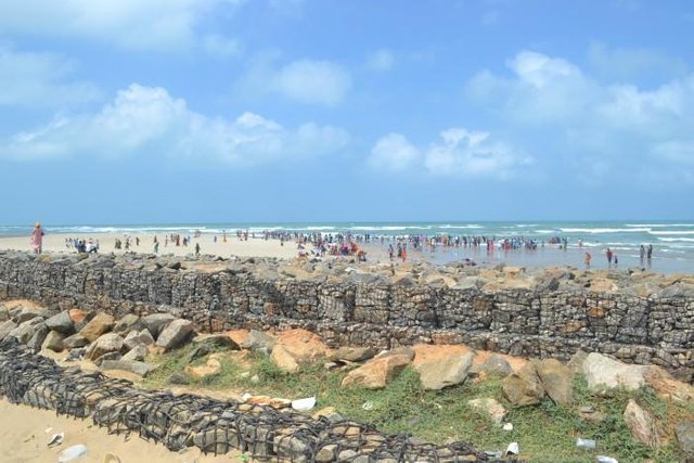 Tourists standing in shallow seawater at Dhanushkoti near the shoreline in Tamil Nadu, India.