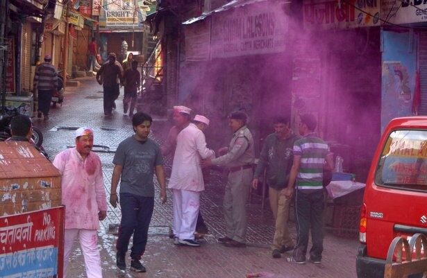 People celebrating Holi on a street in Nainital, with pink colored powder in the air and on their clothes.
