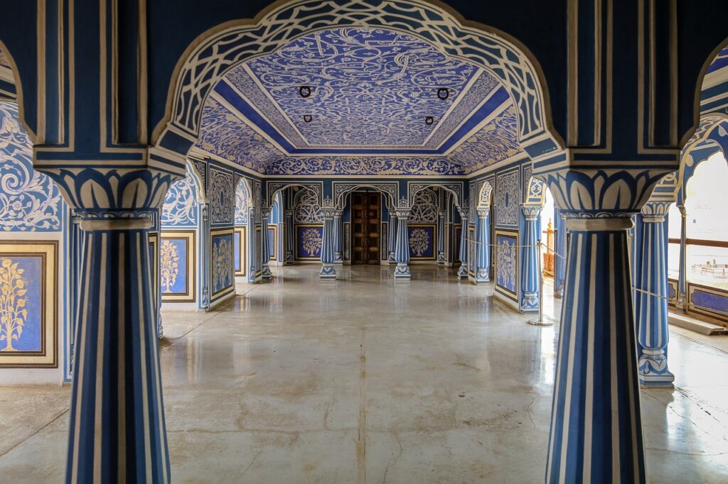 The stunning Blue Room inside Jaipur’s City Palace, featuring intricate floral artwork and ornate arches painted in shades of royal blue and gold.