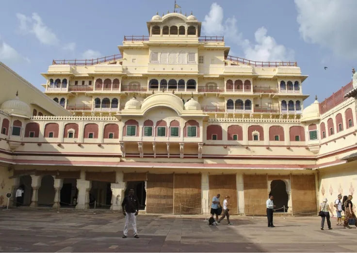 Front courtyard view of the grand City Palace in Jaipur, India, showcasing its stunning blend of Mughal and Rajput architectural styles with intricate balconies, domes, and pastel-colored façades.