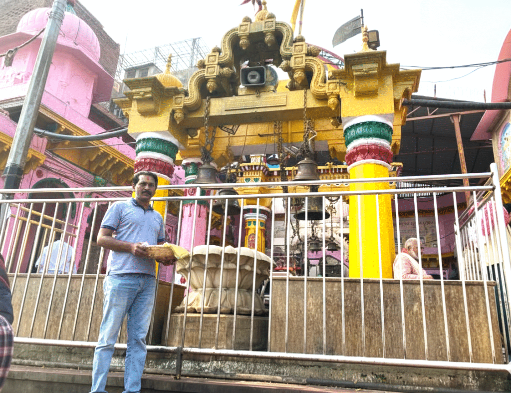 Devotee standing in front of the beautifully painted Dwarakadheesh Temple in Mathura, Uttar Pradesh, India, holding offerings at this iconic temple dedicated to Lord Krishna.