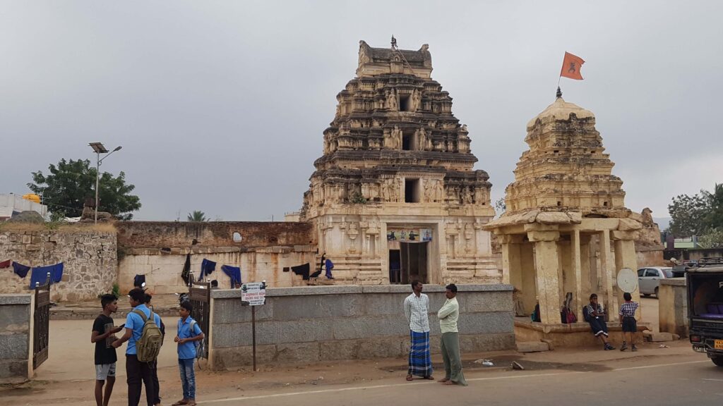 Entrance temple structure in Hampi with people and school children in the foreground.