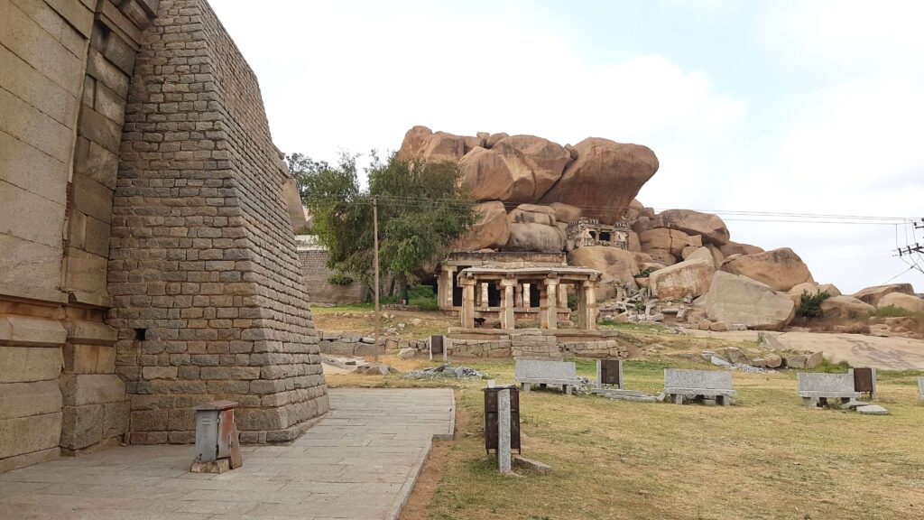 Ancient stone structures and small shrine among massive boulders at Hampi, with weathered walls and quiet surroundings.