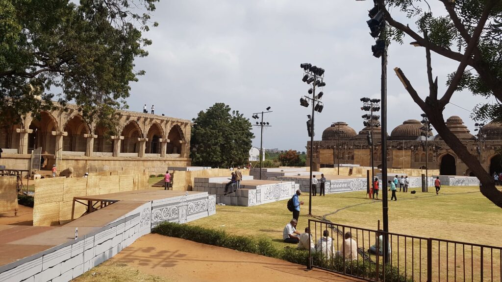 View of the Guards’ Quarters and Elephant Stables at Hampi, with preparations for an event taking place on the lawn between them.