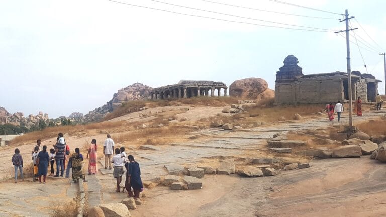 Panoramic view of Hampi’s rocky hills rising above palm groves and village structures in the historic landscape of Hampi, Karnataka.