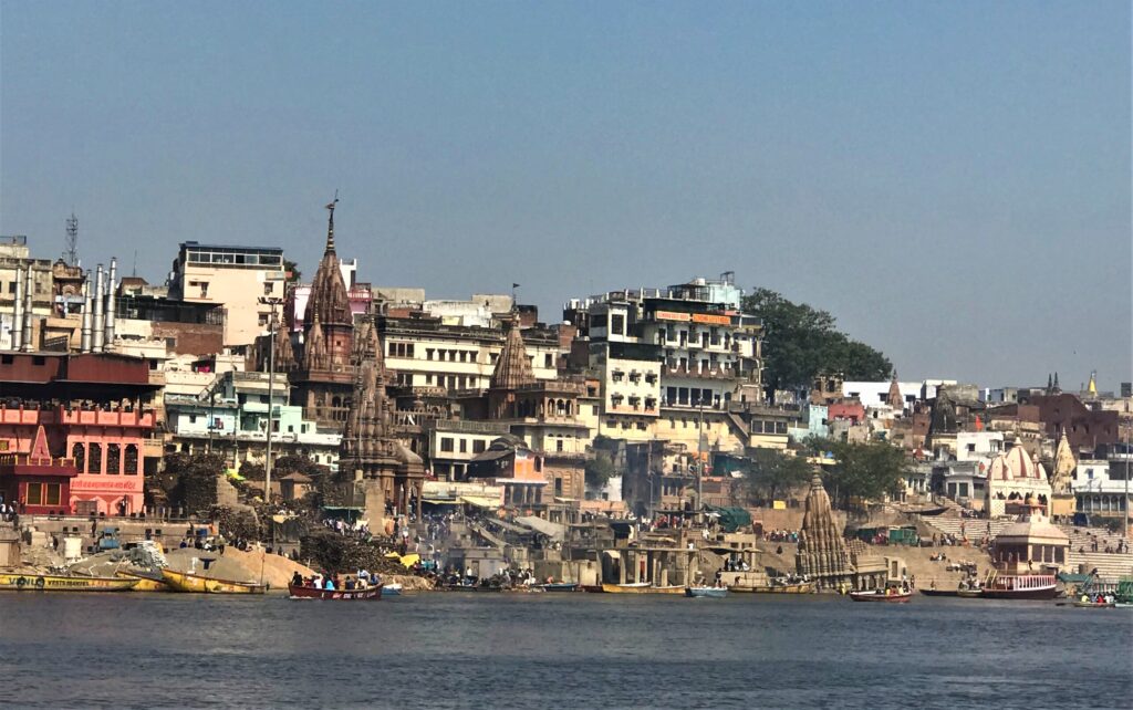 Manikarnika Ghat in Varanasi, with its red sandstone temples and sacred cremation fires, symbolizing the city’s timeless cycle of life and death along the Ganges.