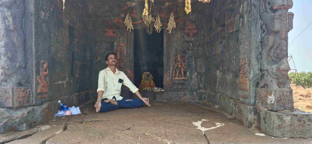 Person meditating inside the ancient stone structure at Sarvanjapeetha in Kudajadri