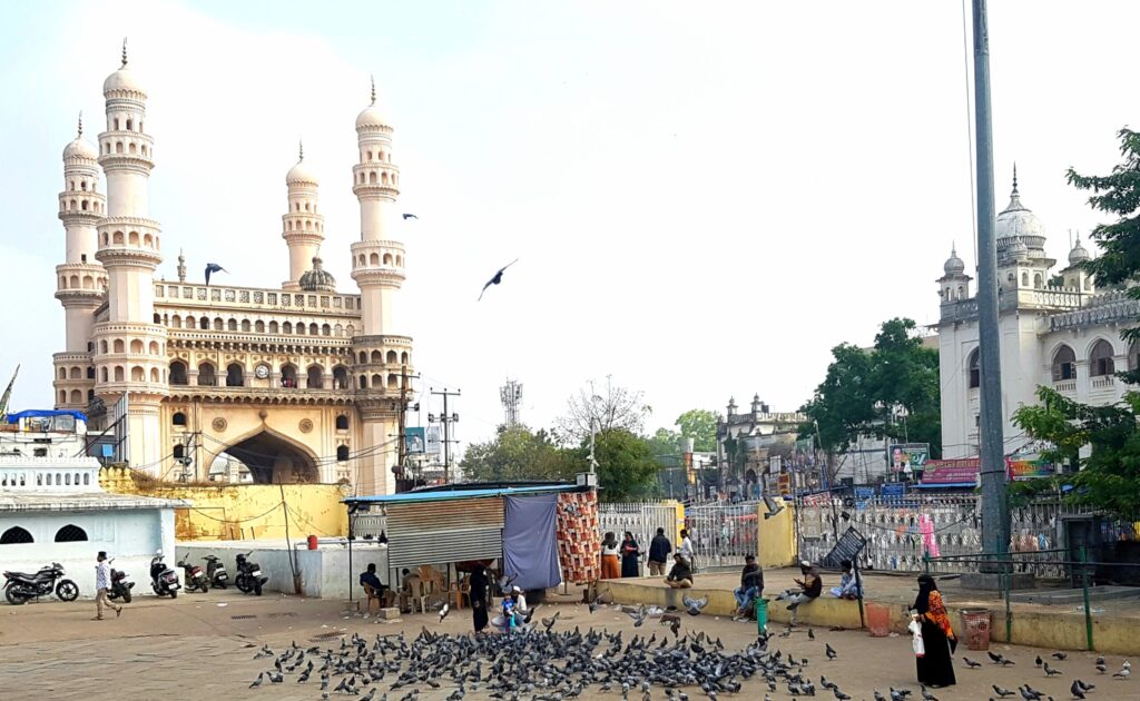 Charminar in Hyderabad with people and pigeons in the foreground, showing the lively surroundings of the monument.