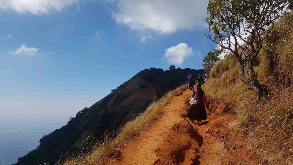 Steep narrow trail on the Kudajadri ridge with trekkers walking along the edge