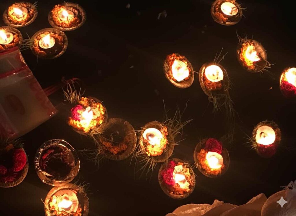 Lit diyas decorated with flowers floating on dark water during a ritual offering.