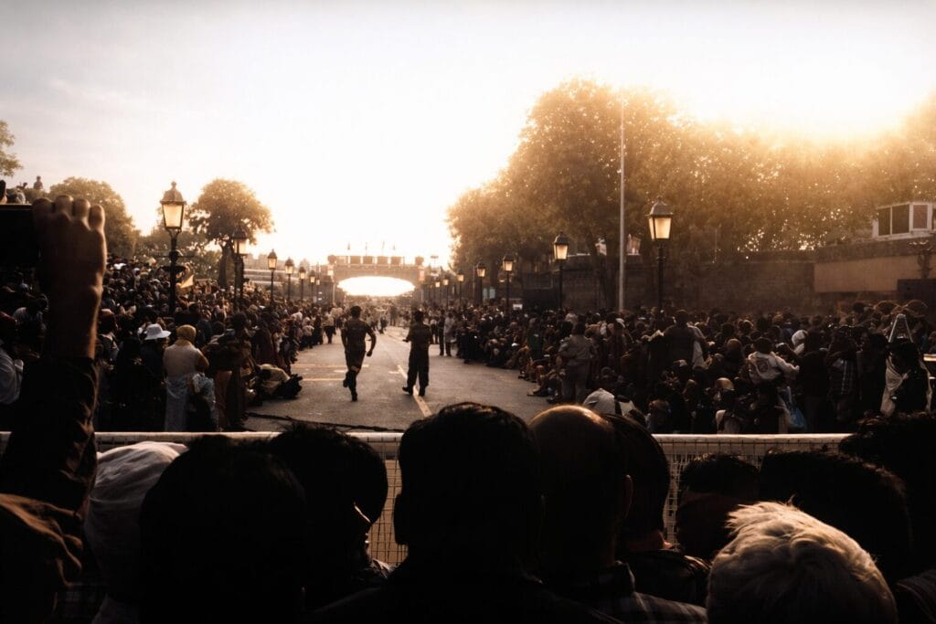 BSF soldiers marching along the parade road at Wagah Border during sunset, as large crowds line both sides to witness the Beating Retreat ceremony.