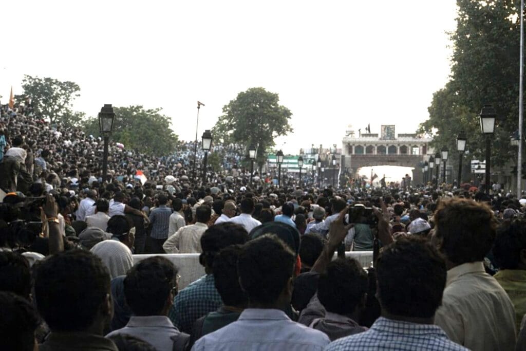 Crowd gathered at the Wagah Border during the evening retreat ceremony, with spectators filling the stands on both sides and the border gate visible in the distance.