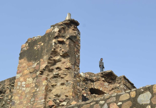 Ruins of Feroz Shah Kotla Fort with visitor standing on ancient wall in Delhi