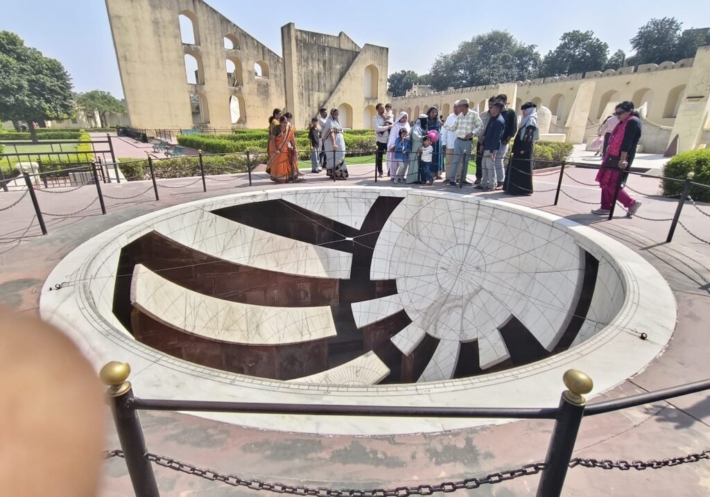 Jai Prakash Yantra at Jantar Mantar Jaipur showing hemispherical sundial with marked celestial coordinates and visitors around