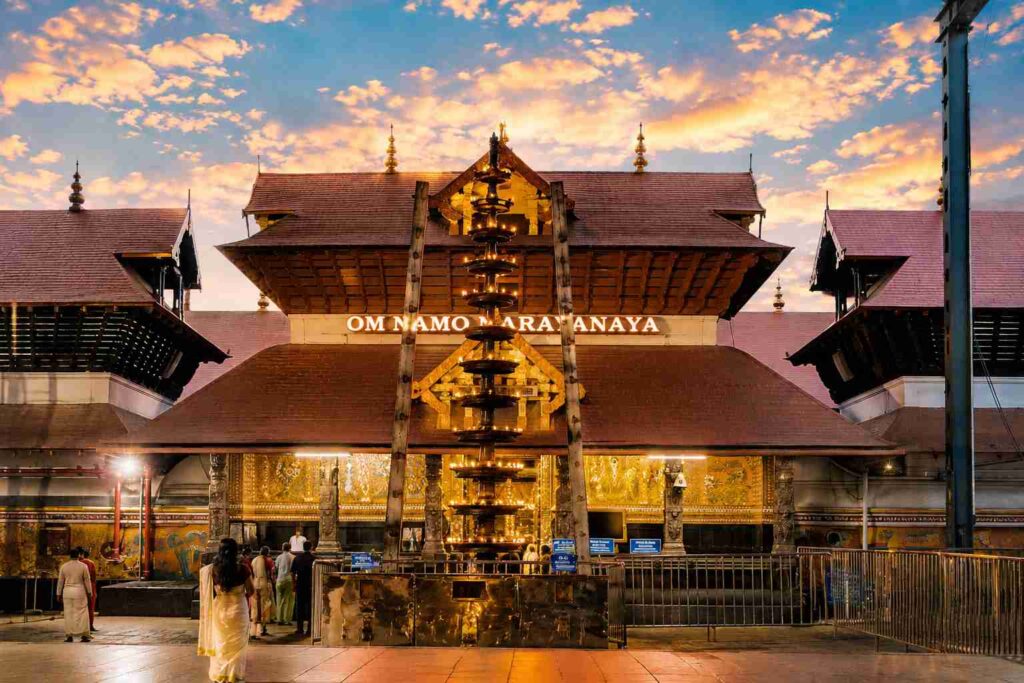 Devotees walking towards Guruvayur Temple during twilight with glowing lamps and “OM NAMO NARAYANAYA” signage illuminating the sacred Kerala temple architecture.
